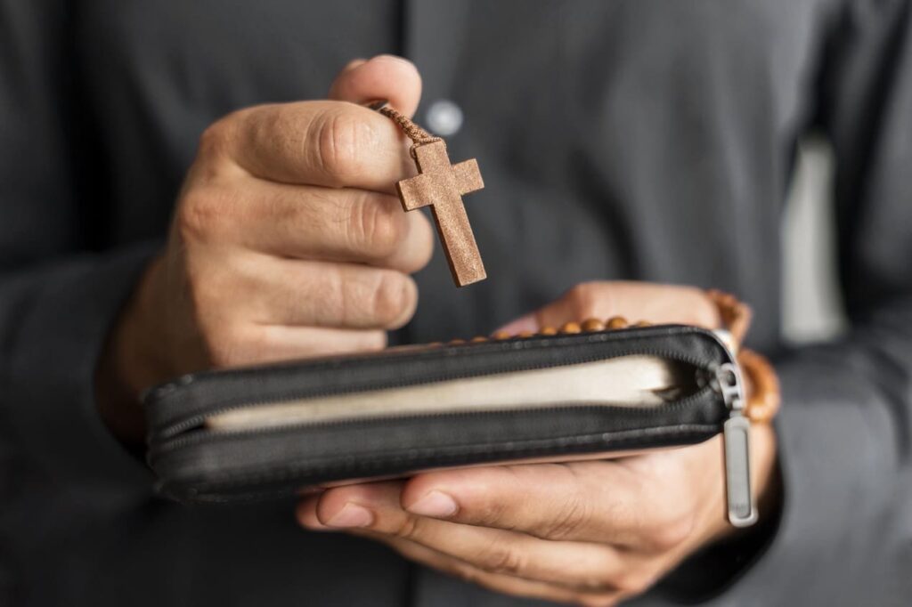 person holding rosary holy book
